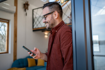 Smiling man using smartphone at home reading good news