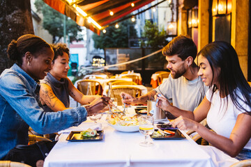 Group of friends enjoying dinner together at outdoor restaurant