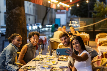 Friends taking selfie while having dinner at outdoor restaurant
