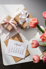 Gifts, bouquet of tulips and calendar for April