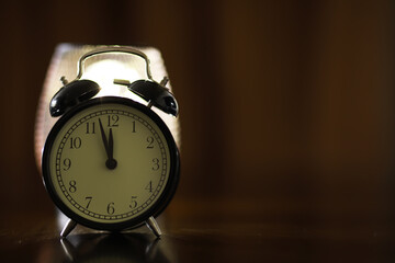 Vintage Black Alarm Clock Showing Midnight or Noon on Wooden Surface with Soft Focus Background
