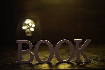 Illuminated BOOK Letters with Soft Focus Background Lighting on Wooden Surface