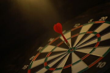 Red Dart Hitting Bullseye on Dartboard in Dimly Lit Room for Challenge and Success Concept
