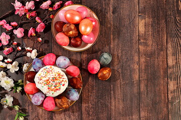 Traditional kulich and marbled Easter eggs painted with onion peel, hibiscus tea and pink matcha with sakura branches, Easter celebration concept, Easter dish ideas for home cooking.