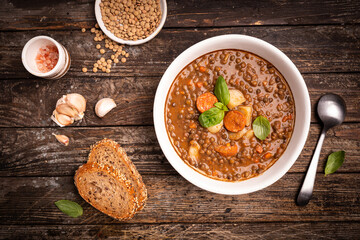 Traditional Spanish dish of lentil stew with chorizo and potatoes on a wooden background. Top view composition. . High quality photo