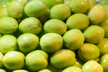 Green juicy jujubes displayed at a bustling local market for fresh produce.