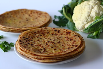 Delicious gobi paratha served alongside a fresh cauliflower bulb with leaves.