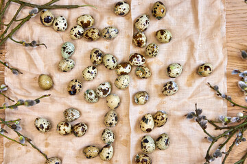 top view of quail eggs and willow branches in beige on linen towel, Easter background