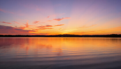 Obraz premium Serene sunset over calm lake reflecting colorful sky 