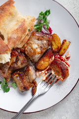 A plate with the remains of a pork kebab, there are no people.
