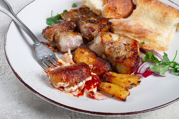 A plate with the remains of a pork kebab, there are no people.