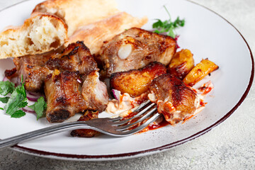 A plate with the remains of a pork kebab, there are no people.