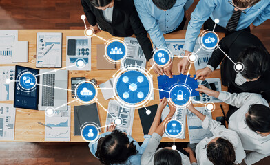 A diverse business team collaborates on data analysis in a modern office setting, featuring charts and digital icons representing technology and security. Amity