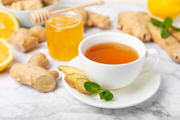 Cup of hot ginger tea with slices of ginger root on wooden background. Warming drink. Alternative medicine. Tea with honey, lemon, ginger and mint. Space for text. Copy space