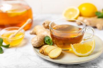Cup of hot ginger tea with slices of ginger root on wooden background. Warming drink. Alternative medicine. Tea with honey, lemon, ginger and mint. Space for text. Copy space