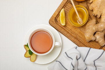 Cup of hot ginger tea with slices of ginger root on wooden background. Warming drink. Alternative medicine. Tea with honey, lemon, ginger and mint. Space for text. Copy space