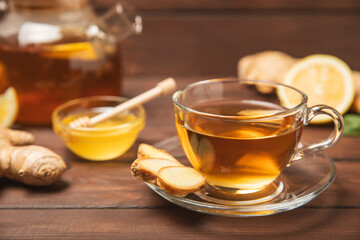 Cup of hot ginger tea with slices of ginger root on wooden background. Warming drink. Alternative medicine. Tea with honey, lemon, ginger and mint. Space for text. Copy space