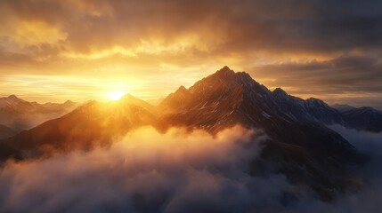 Fototapeta premium A stunning sunset casts golden light over majestic mountains, enveloped by soft clouds, creating a breathtaking natural landscape.