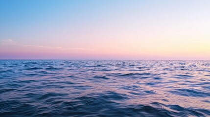 Fototapeta premium A serene ocean view at sunset, showcasing gentle waves and a gradient sky transitioning from blue to pink hues.