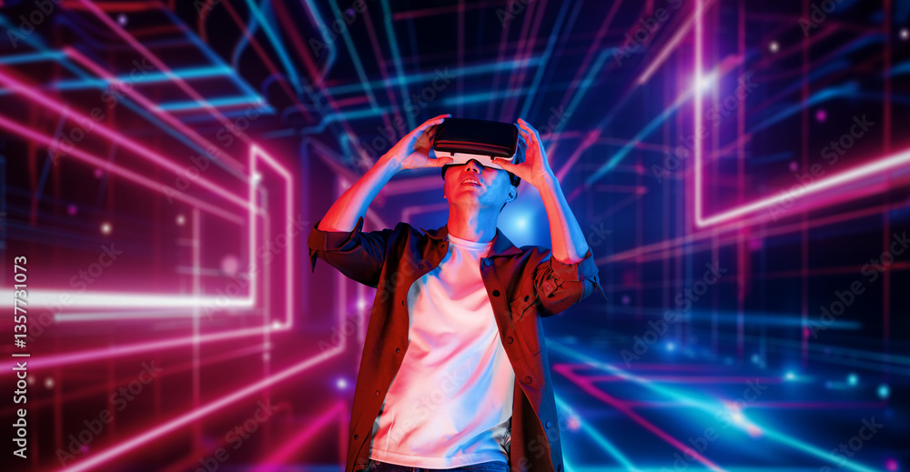 Poster professional male gamer with vr glasses pointing and playing game with glowing neon light. excited p