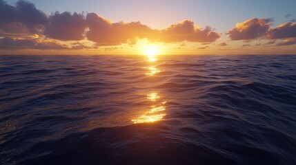 Obraz premium A serene sunset over the ocean, with golden reflections on the water and fluffy clouds, creating a tranquil and picturesque seascape.