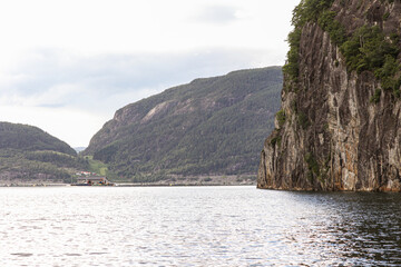 A boat is floating on a lake fjord near a mountain in Norway