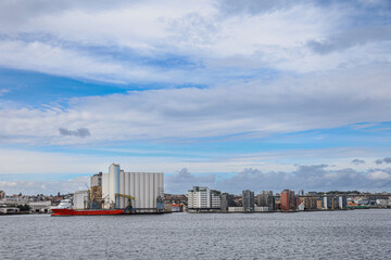 A large red ship is docked at the pier in front of a city skyline Stavanger in Norway