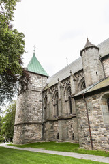 A large stone church building in Stavanger in Norway with a green roof and a steeple