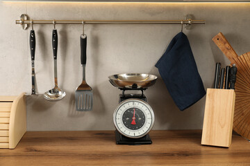 Retro mechanical kitchen scale on wooden countertop and other utensils indoors