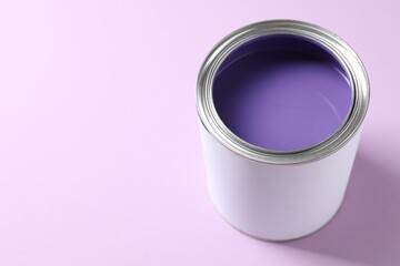 Can of bright paint on violet background, closeup. Space for text