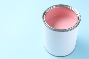 Can of pink paint on light blue background, closeup. Space for text