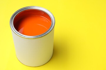 Can of bright paint on yellow background, closeup. Space for text