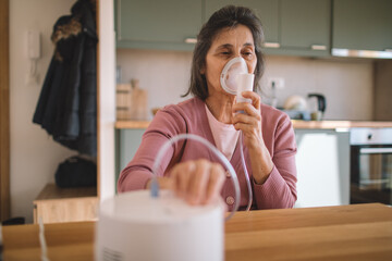 Senior woman administers medication through a handheld device