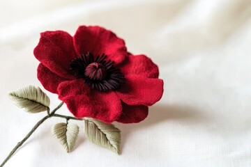 Intricate embroidery creates a lifelike red poppy flower with detailed stem and leaves.