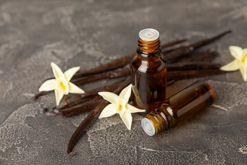 Bottle of vanilla essential oil with vanilla flower on textured background. aromatic vanilla beans. Vanilla extract. Spa concept. Beauty and care. Place for text. Copy space.