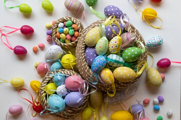 Colorful Easter eggs in various brown wicker baskets of different sizes, with eggs of different colors and decorations, also of different sizes, around the basket and inside. Easter.