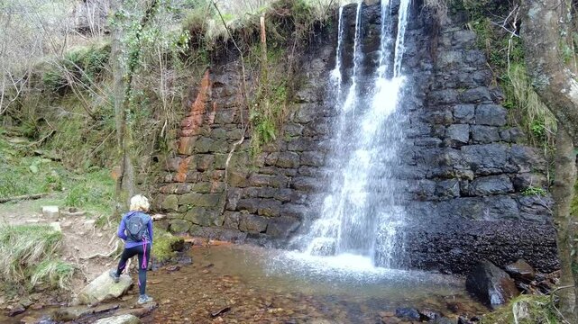 Woman hiking with dog observing waterfall in esles, cantabria