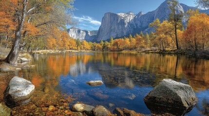 Autumnal landscape reflecting in a calm river, with vibrant fall foliage mirroring in the clear water, showcasing a granite mountain in the background.  Tranquil scene of a national park in the fall
