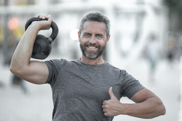Kettlebell workout outdoors. Athletic man lifting kettlebell. Fit guy training with kettlebell....