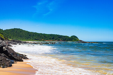 Tranquil Coastal Paradise: Sandy Beach, Rugged Rocks, and Verdant Hills