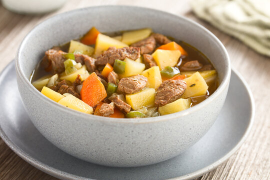 Vegan soup or stew made with vegetable potato, onion, garlic, carrot, green pepper and soy meat chunks, served in bowl (Selective Focus, Focus in the middle of the image)