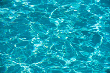 Water background. Blue water, ripples and highlights. Texture of water surface and tiled bottom.
