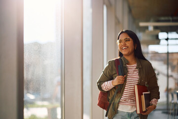 Happy female Indian student at university looking away.
