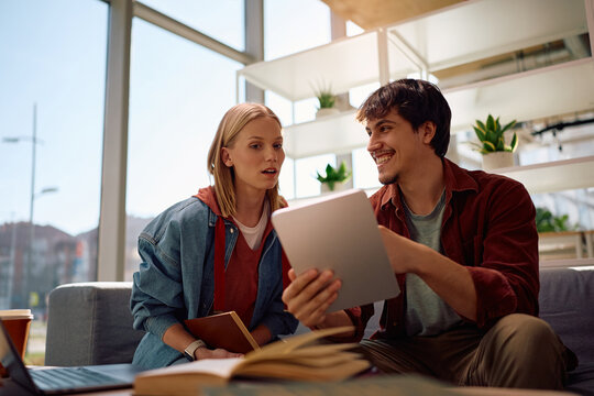 Happy students learning on digital tablet at university.