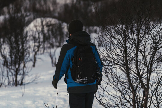 Man walking through snow wearing blue winter coat, Ersfjord Tromso, Norway.