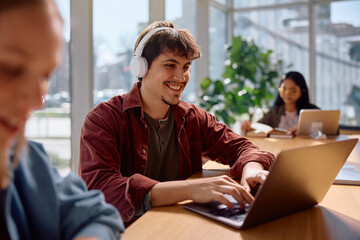 Happy college student e-learning on computer in classroom.