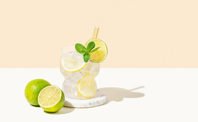 Fresh cocktail mojito with lemon, lime, mint and ice. Citrus lemonade on a white beige background.