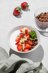 Natural Greek yogurt with homemade chocolate granola, strawberries and banana in a bowl