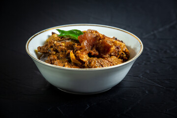 Beef masala or roast, Kerala-style homemade recipe, garnished with curry leaves and served in a white bowl against a black background.