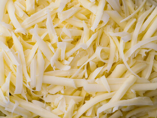 Grated cheese close-up, background. Delicious hard cheese grated on a grater